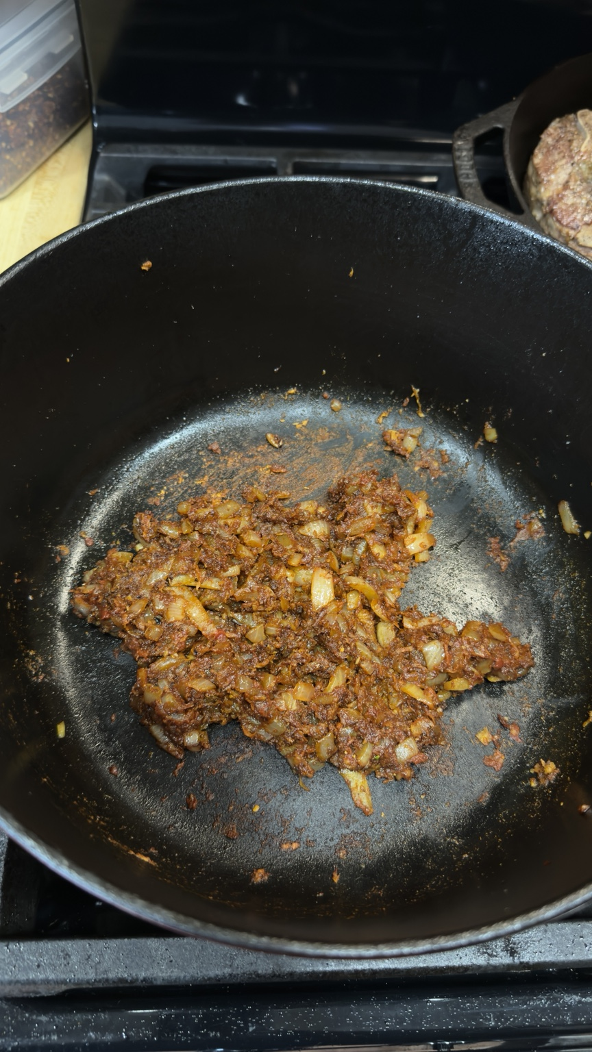 Cooked onion, garlic, ground spices and tomato paste darkened together in a Dutch oven before deglazing.